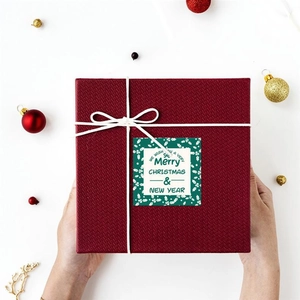 Macro shot of square wine red gift box with Christmas sticker and cotton rope ties