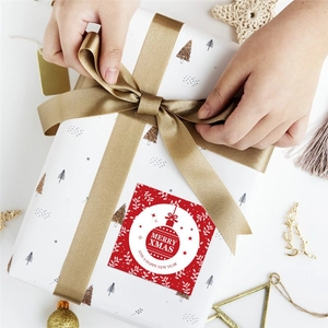 Square red Christmas Merry Xmas stickers on white gift box with gold satin ribbon bow