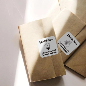 Close-up of cute square weather stickers with thank you text on kraft envelopes