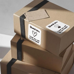 Square white Thank You stickers with heart and flower designs on kraft gift boxes