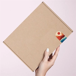 Detail of hand holding kraft paper box with minimalist sun and ocean arch sticker