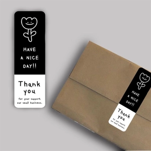 Detail showing black and white rectangular 'Thank you' sticker on a brown cardboard box