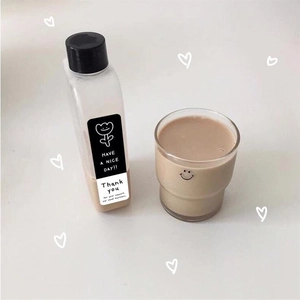 Detail of black rectangular Thank You sticker on a clear bottle and smiling glass cup