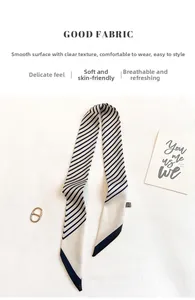Detail eines eleganten Seidenschals in Beige und Marineblau mit goldenem Ring