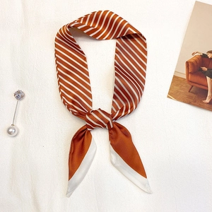 Gros plan sur un foulard twilly à rayures caramel avec texture satinée et nœud élégant