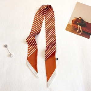 Détail d'un foulard étroit en soie à rayures orange et blanches avec bouts en biais