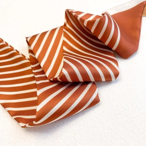 Gros plan d'un foulard étroit satiné à rayures marron et blanc avec une texture soyeuse
