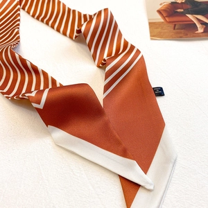 Détail du foulard en soie à rayures orange et blanches avec texture satinée lisse