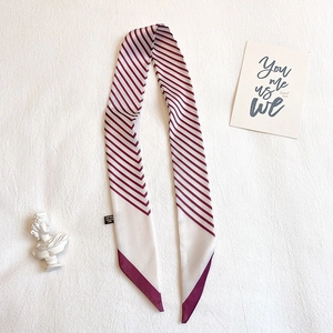 Détail d'un foulard en soie à rayures bordeaux et blanc avec une texture lisse