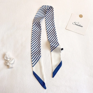 Détail d'un foulard étroit en soie à rayures bleues et blanches sur fond texturé