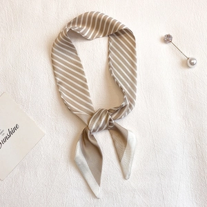 Détail d'un foulard étroit en soie à rayures kaki avec des extrémités pointues