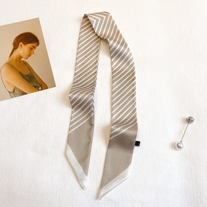 Détail d'un foulard twilly étroit à rayures champagne et blanches avec texture satinée