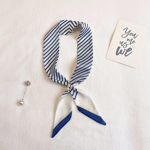 Détail d'un foulard en soie à rayures bleues et d'épingles décoratives en perles