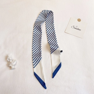 Détail d'un foulard en soie rayé bleu et blanc comme accessoire de mode pour sac chic