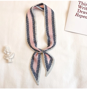 Dettaglio del foulard twilly in seta rosa e grigio con una fibbia ad anello in metallo dorato