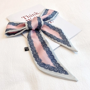 Dettaglio di sciarpa in poliestere rosa con motivo paisley e fiocco elegante
