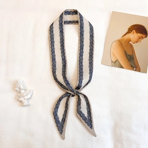 Dettaglio di un foulard Twilly in seta con stampa paisley e pizzo blu su fondo beige