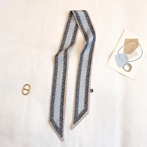 Dettaglio di un foulard in seta azzurro con motivo paisley e fibbia in metallo dorato