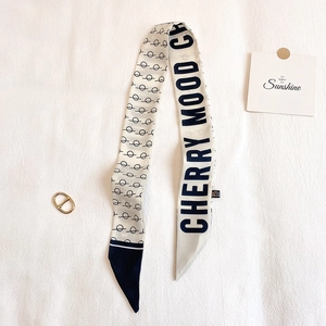 Dettaglio del foulard twilly crema con stampa nera e fibbia ad anello in metallo dorato