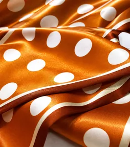 Macro detail of vibrant orange polka dot faux silk fabric with smooth satin texture