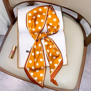 Close-up of a yellow polka dot silk scarf tied on a magazine with golden lipstick