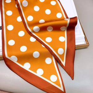 Detail of silk-like satin twilly scarf with orange polka dots and deep red border