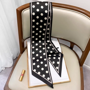 Close-up of a long black and white polka dot silk scarf draped on a wooden chair