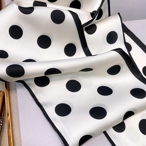 Detailed close-up showing soft satin texture and black polka dot pattern on silk scarf