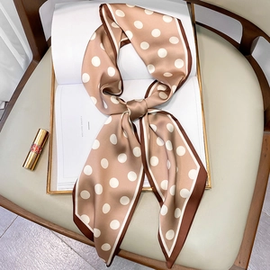 Detailed view of a brown polka dot silk scarf styled as a bow on a magazine page