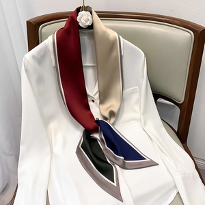 Close-up of a multi-color patchwork silk scarf styled on a white chiffon shirt collar