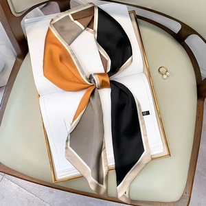 Close-up of geometric silk-like narrow scarf with orange and black blocks on a magazine