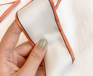 Détail de l'écharpe en soie sergée montrant le lustre satiné doux et la bordure orange
