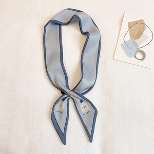 Détail du foulard twilly en soie bleu clair avec broderie ananas et boucle en anneau doré