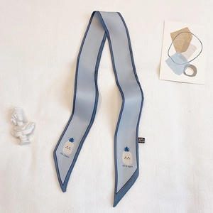 Détail d'un foulard twilly bleu clair en polyester avec motif ananas et étiquette