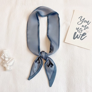 Détail du foulard en soie bleu-gris avec motifs géométriques et bordure bleu marine