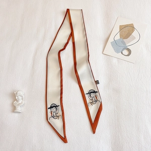 Détail d'une écharpe en soie étroite avec portrait de femme abstrait et bordure orange
