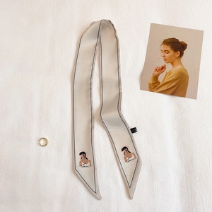 Détail d'un foulard en satin champagne avec illustration minimaliste et texte artistique