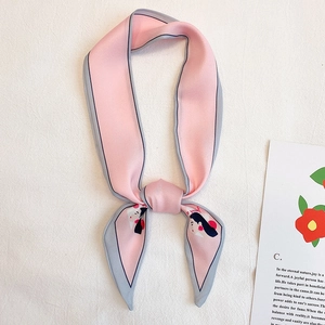 Détail d'un foulard en soie rose et gris avec portrait illustré et motif floral
