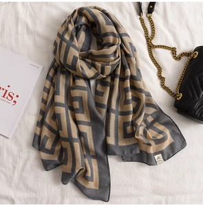Detail of geometric scarf in grey and khaki tones with magazine and chain bag props