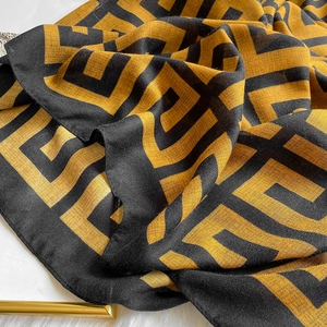Close-up of geometric pattern on cotton linen scarf with elegant gold and black color contrast