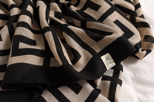 Detail of geometric pattern scarf with cotton linen texture and stitched logo label