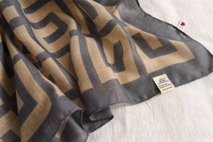 Detail view of Greek Key pattern on soft cotton-linen scarf with brand label