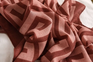 Close-up of geometric pattern scarf with brick red tones and soft textured linen feel