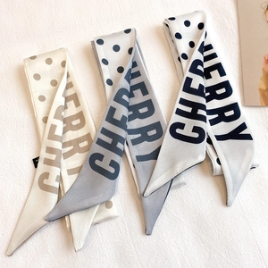 Detailed macro view of three narrow polka dot Twilly silk scarves with CHERRY lettering