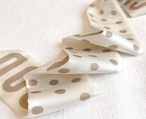 Detailed macro view of polka dot long silk scarf with soft texture and elegant lettering