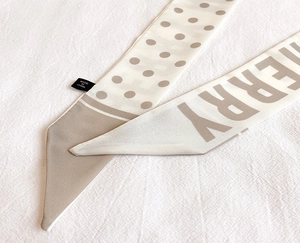 Detailed close-up of beige polka dot silk scarf with fabric care label and print