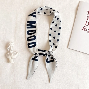Close-up of elegant polka dot silk scarf with letter print on stylish texture