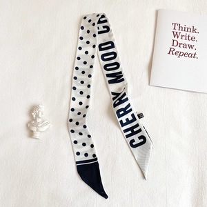Close-up of a polka dot silk twilly scarf with Cherry Mood lettering and chic decor