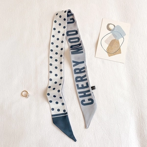 Detailed view of polka dot long skinny scarf used as a hair tie and handbag ribbon