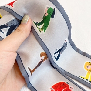 Detailaufnahme von Seidenschal mit Comic-Illustrationen, blauem Rand und Satin-Glanz